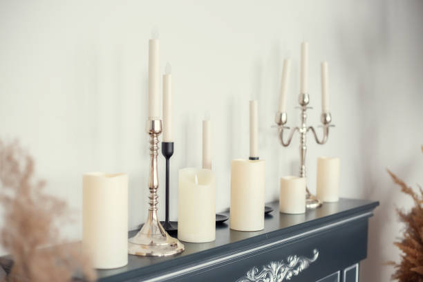 istock Candles of various types and sizes with and without candlesticks on the imitation fireplace countertop near the wall 1304972377