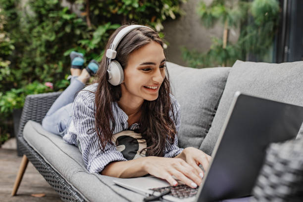 istock Young woman is relaxing while using laptop at home on the balcony 1304973334