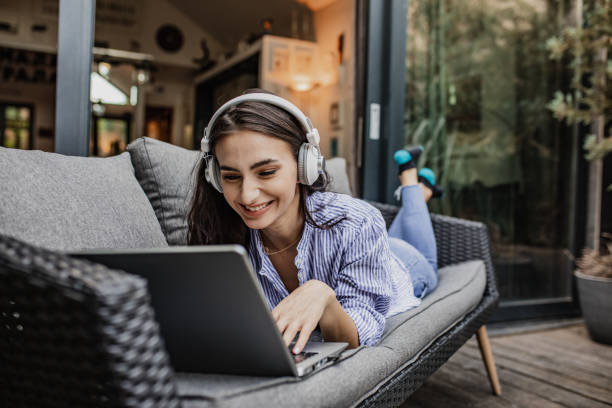 istock Young woman is relaxing while using laptop at home on the balcony 1304973343