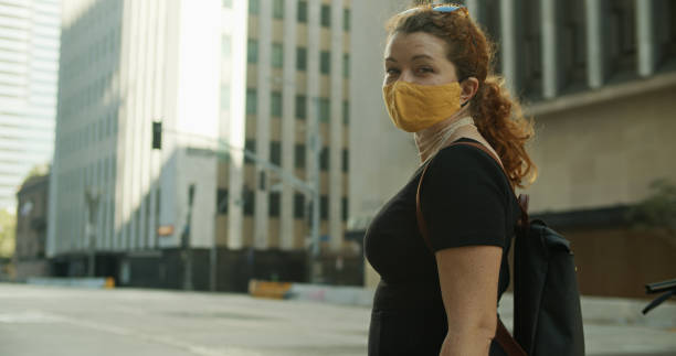 istock Lone Masked Woman Smiles from Behind a Face Mask 1304974146