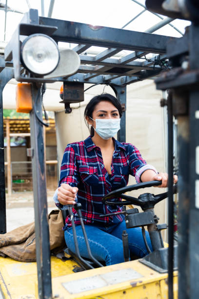 istock woman in protective face mask working on forklift 1304976281