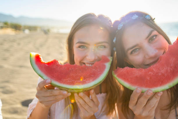 istock Two women eating watermelon and looking at the camera. 1304977652