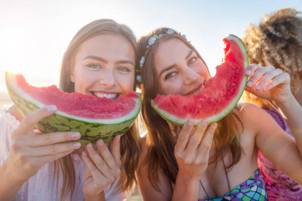 istock Two women eating watermelon and looking at the camera. 1304977673