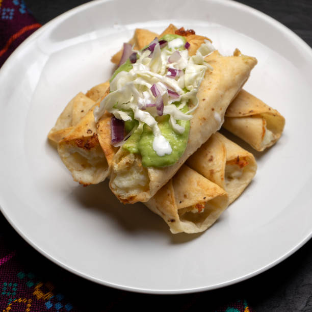 istock Fried tacos called flautas with guacamole and cabbage on dark background. Mexican food 1304987949