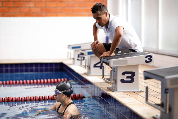 istock Coach between starting blocks giving instructions to one armed female swimmer inside the pool 1304988859
