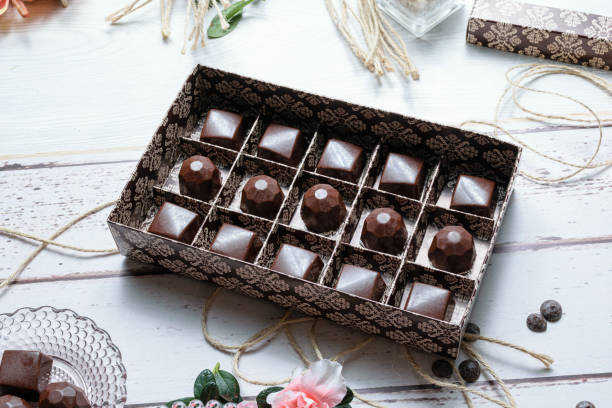 istock Brown box with several chocolate candies, on twine rope. Next to chocolate callets. 1304989944