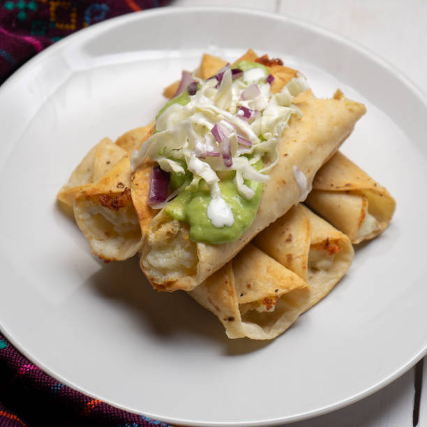istock Fried tacos called flautas with guacamole and cabbage on white background. Mexican food 1304989992