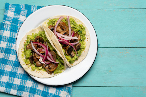 Mushroom and guacamole tacos on turquoise background. Traditional mexican food