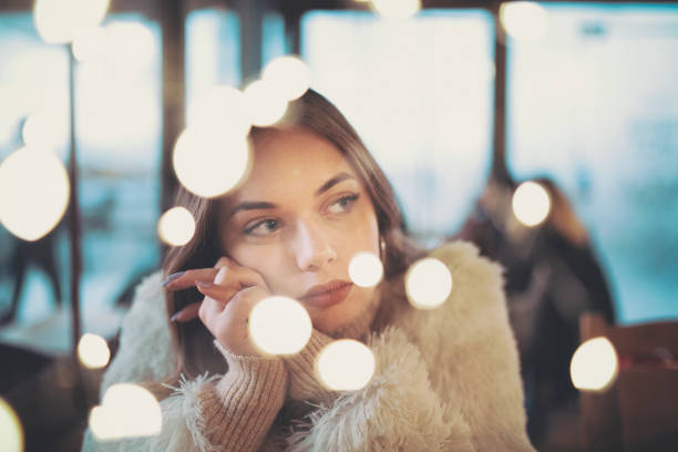 Causian sad lonely young woman looking thoughtfully through the window during pandemic, and celebrating christmas alone, shot with canon 5dsr