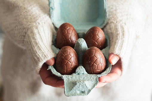 Woman hands holding egg carton with chocolate eggs. Easter celebration concept