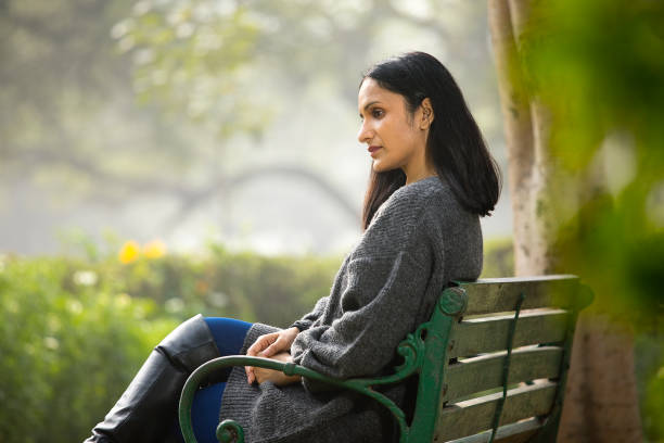istock Thoughtful woman sitting on bench 1305014151
