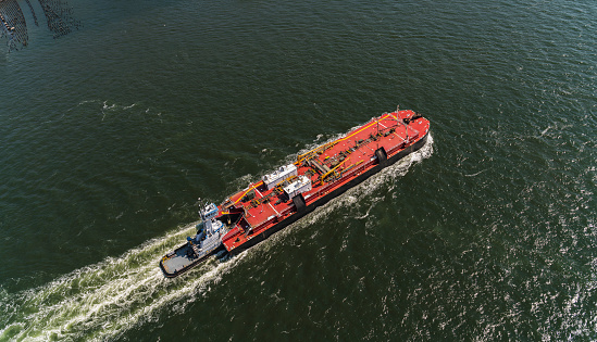 A small pilot boat sails between two large ships