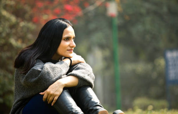 istock Thoughtful woman sitting at park 1305021104