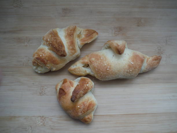 istock Freshly baked croissants lying on a table over a black background. 1305021252
