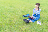 アジアの女子学生は、草原でラップトップPCを使用しています。