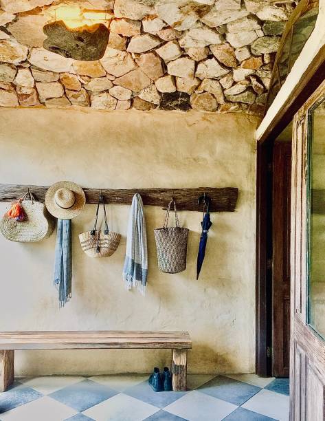Entrance with Sand Stone Ceiling Tiles Floors and Hanging Rack Vertical still life of or design foyer lobby entrance of luxury tuscan style designer home with earthy neutral color tones of sand stone rock ceiling rustic wood large Moroccan tiles and hanging bags hat and umbrella wall hook rack hanging stone stock pictures, royalty-free photos & images