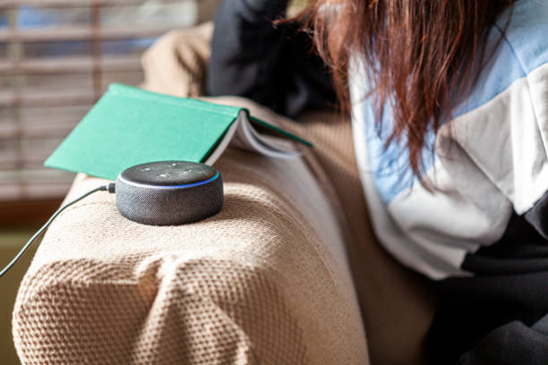 mulher fazendo pergunta ao dispositivo de ponto amazon echo - hardcover book audio - fotografias e filmes do acervo