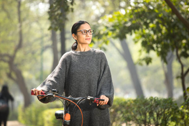 istock Woman walking and pushing bicycle at park 1305026996