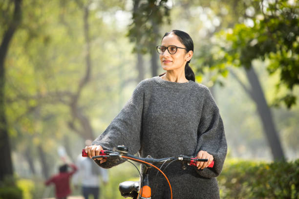 istock Woman walking and pushing bicycle at park 1305027084