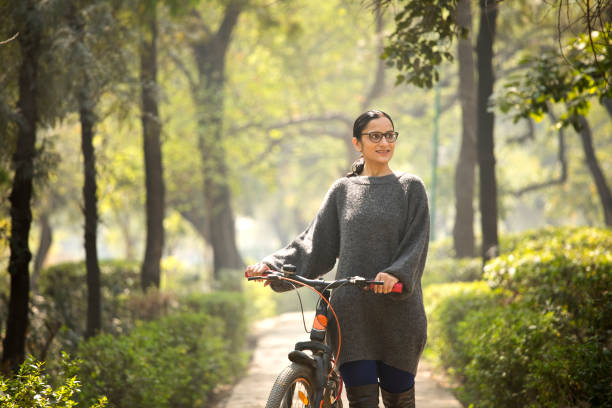 istock Woman walking and pushing bicycle at park 1305027720