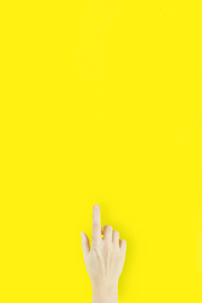 istock Hand Pointing Against Yellow Background. Index Finger Pointing Forward 1305027833