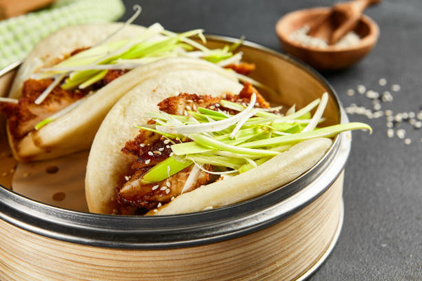 bao brötchen mit hoisin huhn. bambusdampfer auf dunklem schiefertisch. chinesisch, asiatisch, authentisches essenskonzept - baozi stock-fotos und bilder