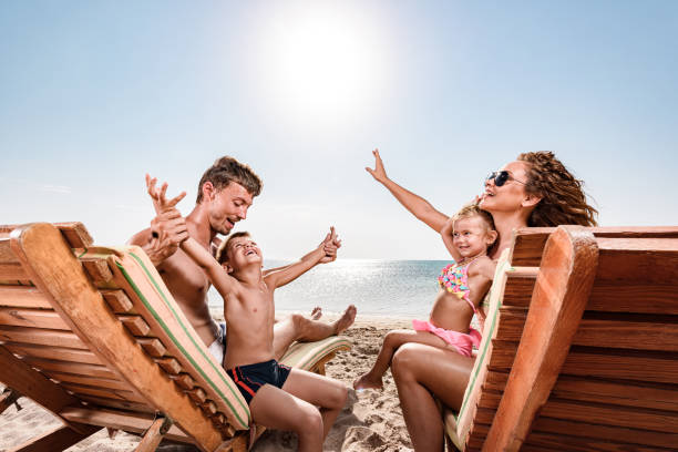 istock Young happy family having fun on deck chairs at beach. 1305032928