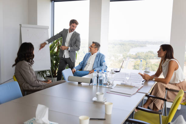 istock Young businessman drawing graph on flip chart for colleagues at the conference table 1305034319
