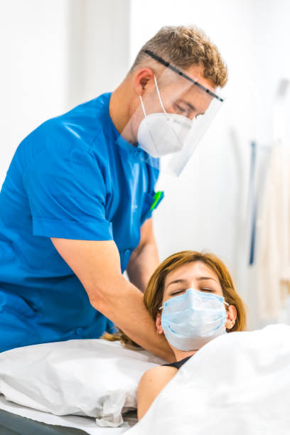 istock Structural osteopathy of a physiotherapist with protective measures for a patient on the stretcher. Covid-19 pandemic. Osteopathy, therapeutic chiromassage 1305038592