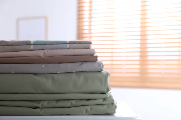 istock New clean folded bed linens on table indoors. Space for text 1305038959