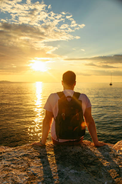 istock man with backpack enjoying sunset over the sea 1305039890