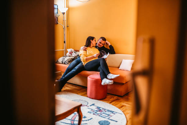 istock Couple on sofa in modern home with magazine 1305040030