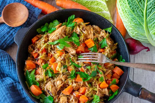 slow cooked turkey breast with brown rice, savoy cabbage and carrot vegetables served in a pan from above. Ready to eat