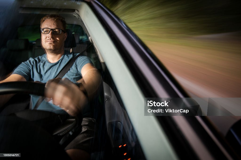 Handsome young driver driving hic car Handsome young driver driving hic car fast yet safely on the road 35-39 Years Stock Photo
