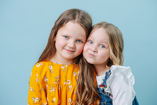Portrait of two sisters close-up on a blue background