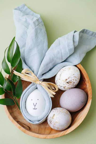 istock Easter egg in a napkin along with gilded eggs in a wooden bowl 1305048113