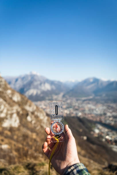 male hand with compass, mountains range in background, sunny day - travel vertical tourist switzerland imagens e fotografias de stock