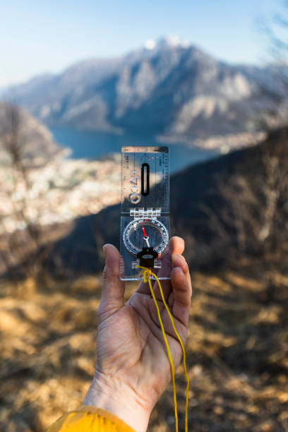istock Male hand with compass, mountains range in background, sunny day 1305048130