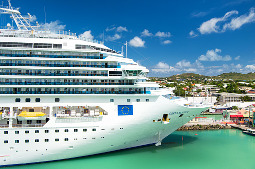 St. John, Antigua - March 05, 2016: beautiful large cruise ship, big white passenger boat, luxury modern Costa Magica vehicle at moorage in sea port, pier on summer blue cloudy sky. summer vacation