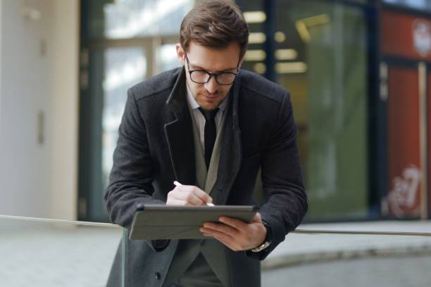 istock A handsome young executive working on his digital tablet outdoors 1305049600