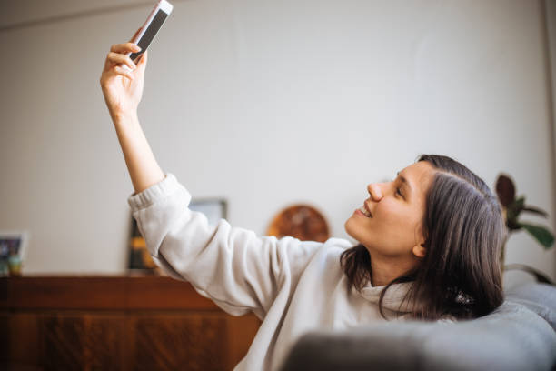 istock Young woman in her apartment taking selfie 1305057094