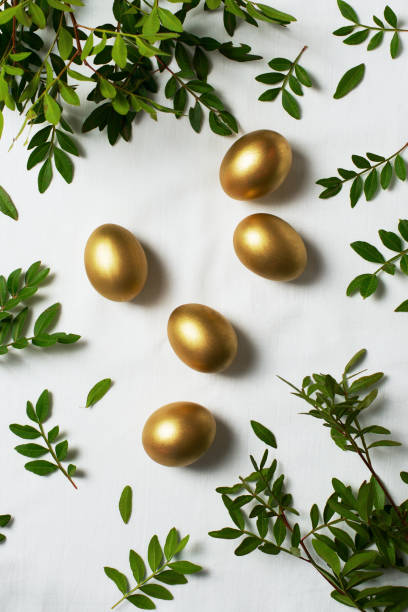 istock Easter concept with gold eggs and branch with green leaf on white background 1305058254