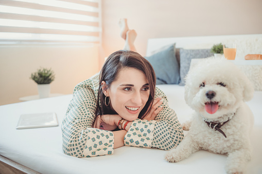 A beautiful woman at home with a dog in bed. Weekend vacation in your home.