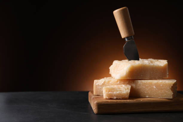 Delicious parmesan cheese with knife on black table. Space for text Delicious parmesan cheese with knife on black table. Space for text grana padano stock pictures, royalty-free photos & images