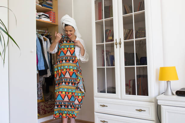 istock Young woman choosing her dress and getting ready while dressed up in bath robe. 1305064870