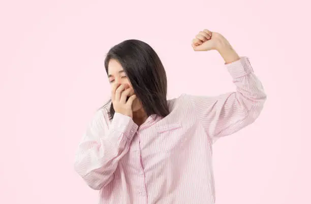 woman wear pink pajamas yawn and stretch when her wake up feeling sleepy