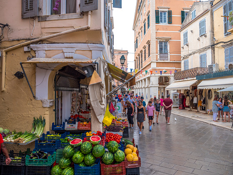 Tourism, People shopping and eating on a narrow street in old town Corfu, Greece
