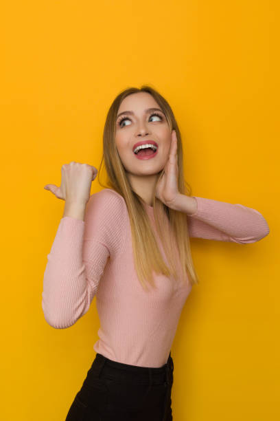 istock Excited Young Woman Points With Thumb Behind Herself. 1305078046