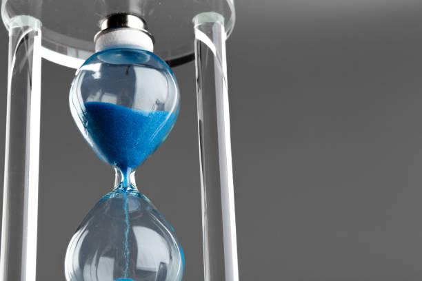 istock Blue hourglass on gray background close up 1305078114