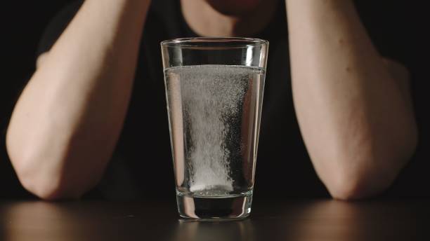 istock Man sits in front of glass with effervescent dissolving pill 1305081497